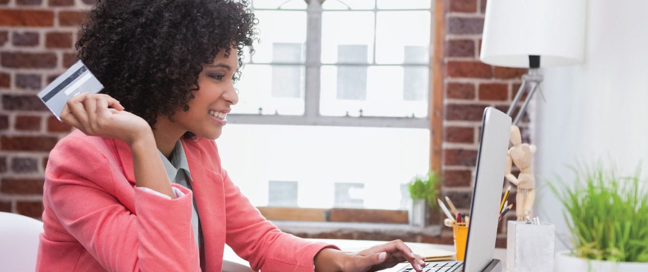 a woman at work holding her credit card and checking her computer