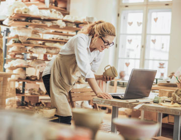 a woman in her workshop checking her computer