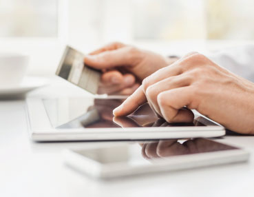 someone holding a credit card and using a tablet 