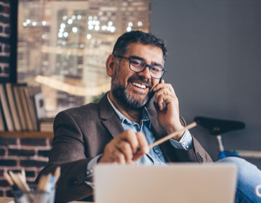 man talking on the phone and looking at his computer