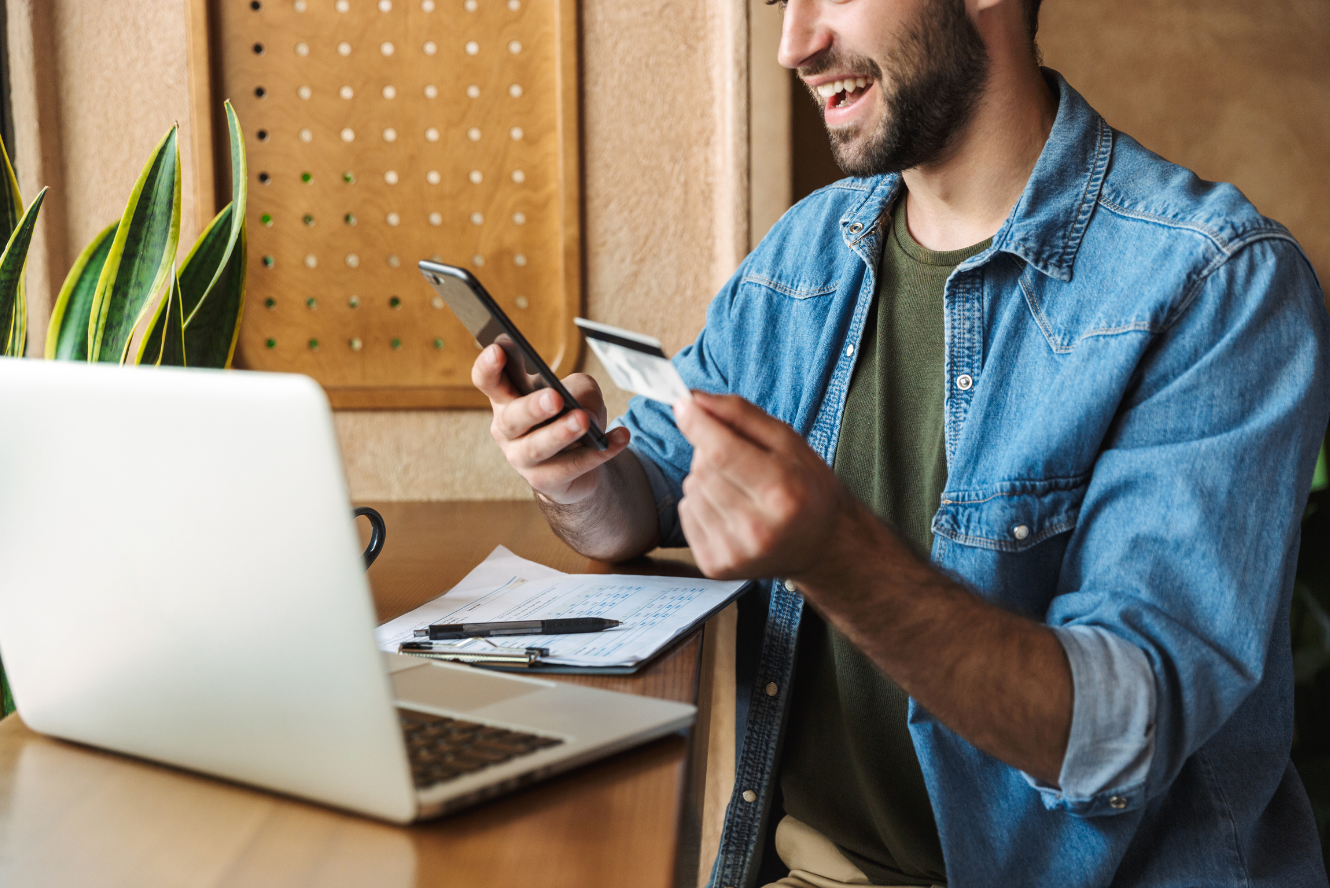 A man viewing information on his phone while holding his card. 