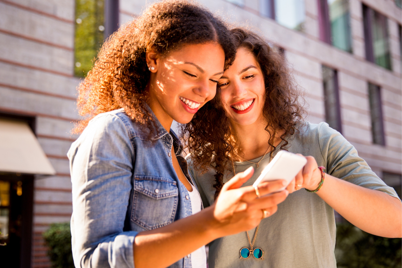 Two friends looking at banking information on a phone. 