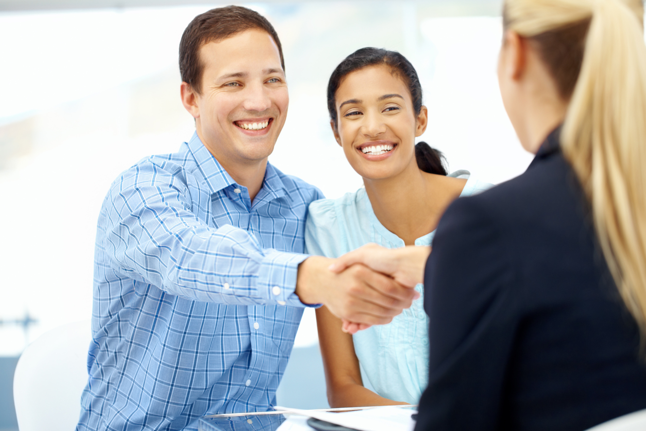 A young couple shaking hands with a banker. 